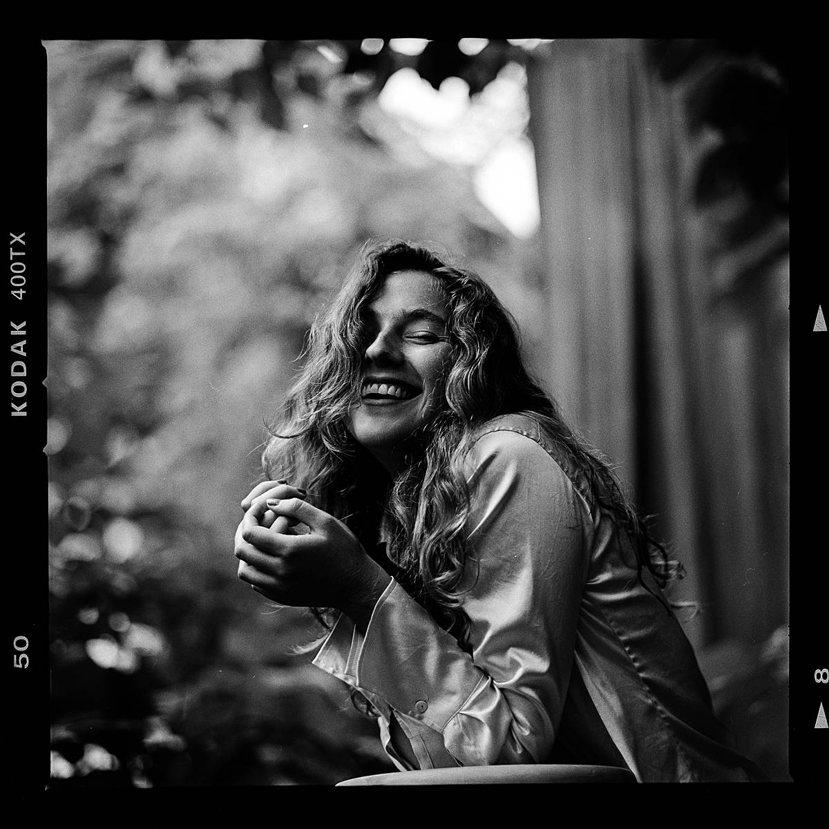 black and white film portrait of girl laughing in outdoor studio taken on hasselblad 202fa and 110mm f2 lens